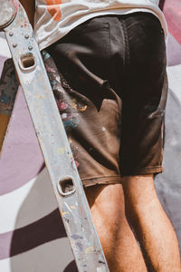 Midsection of man standing on ladder