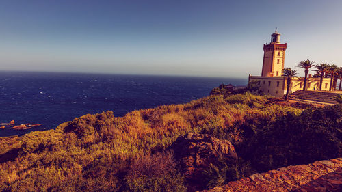 Lighthouse by sea against sky