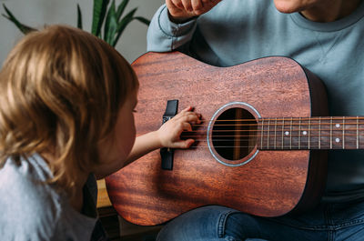 Little girl plays the guitar with her mother on the floor at home