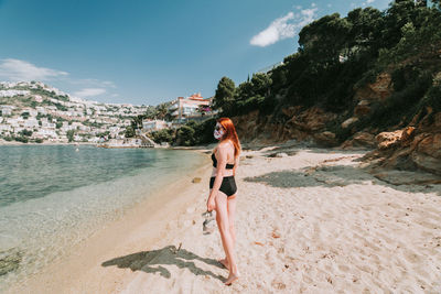 Woman standing on beach by sea against sky