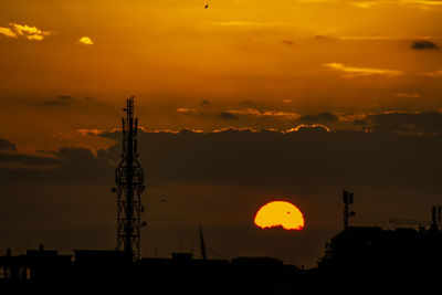 Silhouette communications tower against sky during sunset