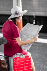 Rear view of young woman reading book