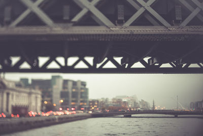 Bridge over river in city against sky