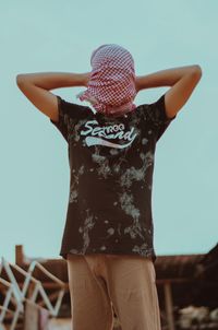 Rear view of woman wearing hat standing against wall