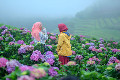 Rear view of woman with pink flowers on field