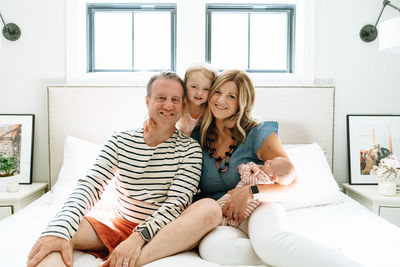 Closeup portrait of a family of four sitting together on a bed