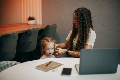 Mom untwists daughter's pigtails at home