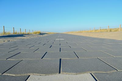 Empty road against clear blue sky