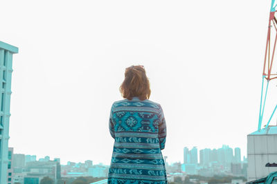 Rear view of woman looking at city buildings against clear sky