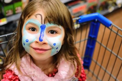 Close-up portrait of girl with face paint in shopping cart