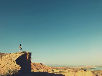 Man standing at cliff against sky