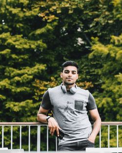 Portrait of young man standing against railing