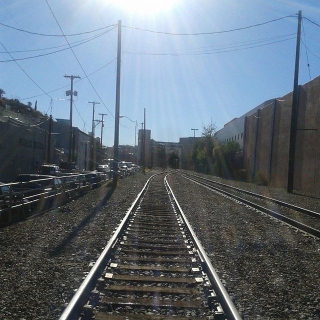 railroad track, transportation, the way forward, rail transportation, diminishing perspective, vanishing point, built structure, building exterior, architecture, sky, public transportation, power line, railway track, electricity pylon, cable, railroad station, city, day, railroad station platform, long