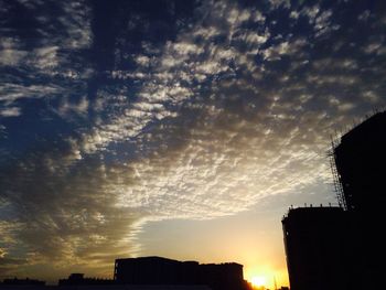 Low angle view of silhouette buildings against sunset sky