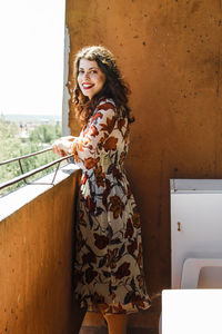 Portrait of smiling young woman standing in balcony