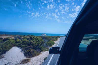 Road by sea against blue sky