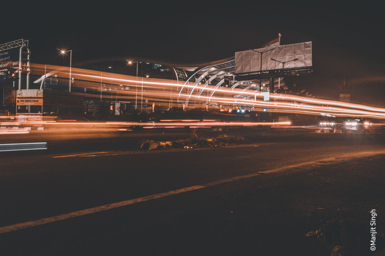 LIGHT TRAILS ON ROAD IN CITY AT NIGHT