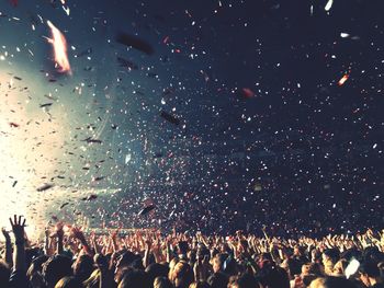 Crowd at music concert against sky at night