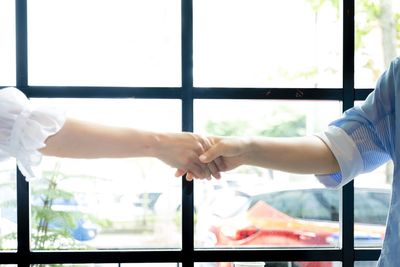 Midsection of woman hand holding glass window