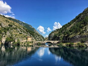 Scenic view of river amidst mountains against blue sky