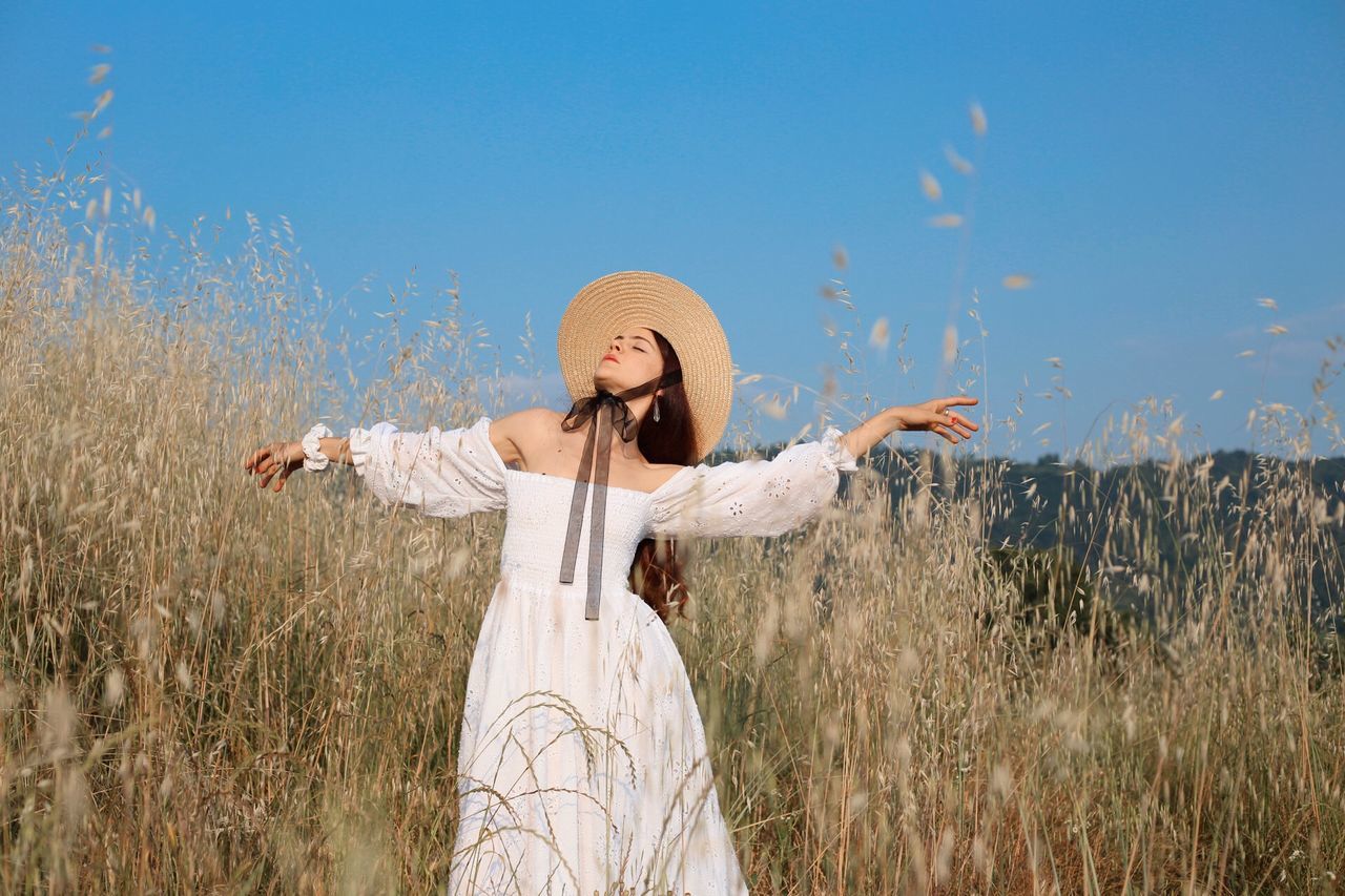 WOMAN STANDING BY PLANTS ON FIELD