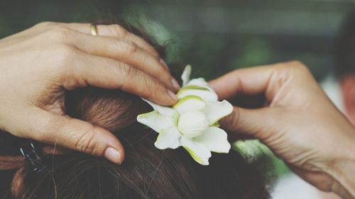 Cropped hands adjusting flowers in her hair