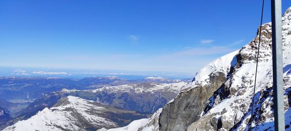 Scenic view of snowcapped mountains against blue sky