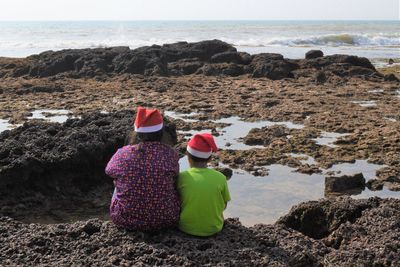 Rear view of women on rocks at beach