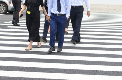 Low section of colleagues crossing road in city