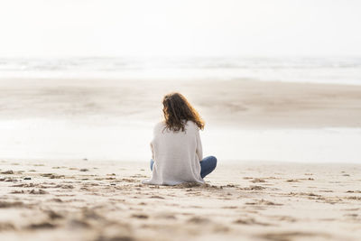 Rear view of woman sitting on beach