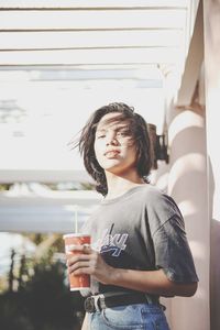 Young woman drinking glass while standing outdoors