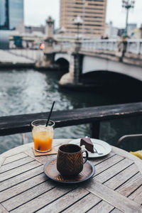 Close-up of food and drink on table against river in city