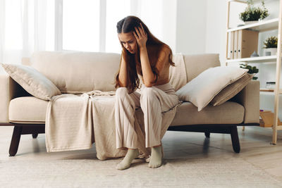 Young woman using mobile phone while sitting on sofa at home