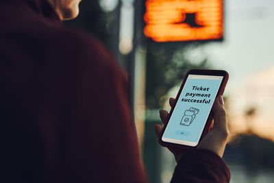 Buying ticket online near bus stop before ride. person paying for ticket using mobile payment app