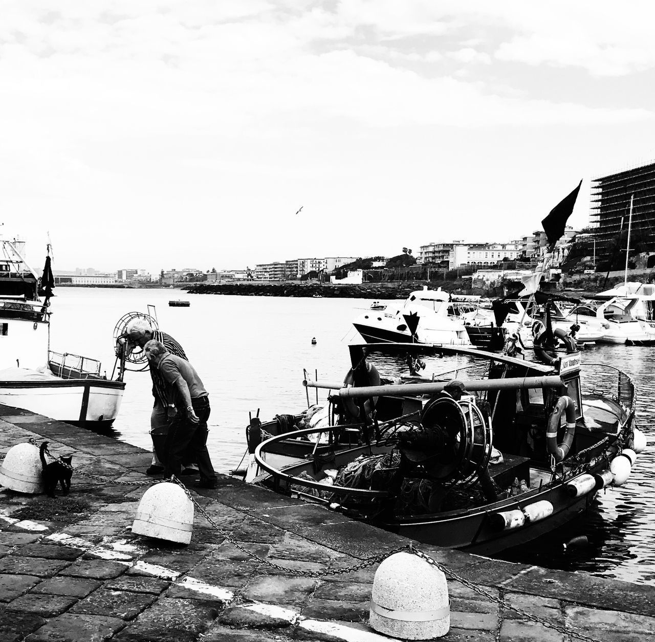 MAN FISHING AT HARBOR AGAINST SKY