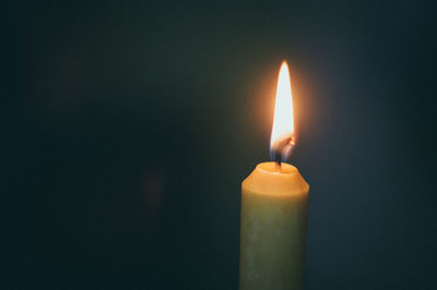 Close-up of lit candle in darkroom