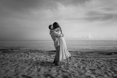 Couple kissing at beach against sky 