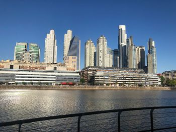 Modern buildings by river against sky in city