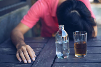 Midsection of man sitting by glass on table