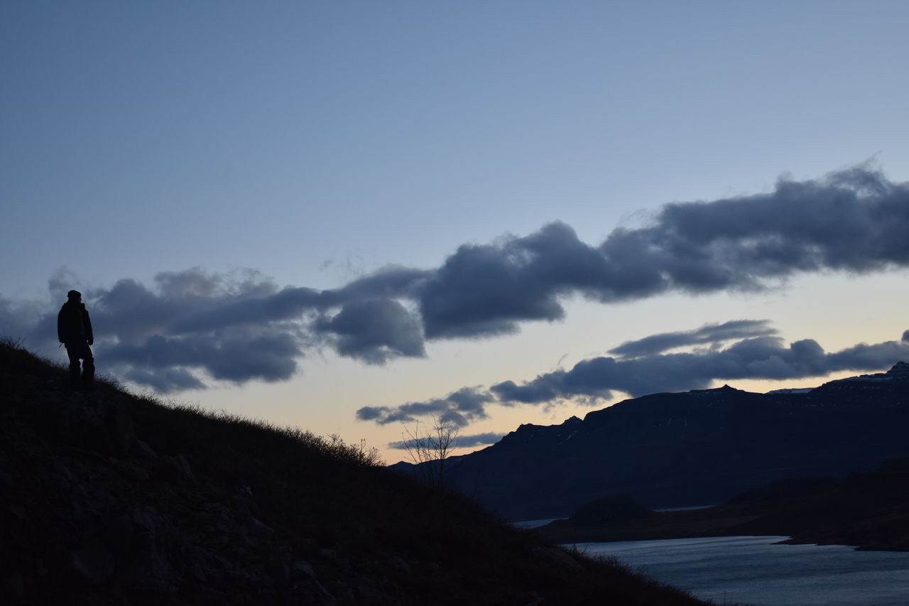 SILHOUETTE MAN STANDING ON MOUNTAINS AGAINST SKY