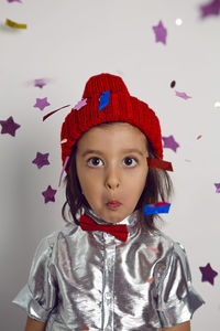 Portrait surprise in knitted hat boy child in silver shirt and red bow tie catches glitter confetti