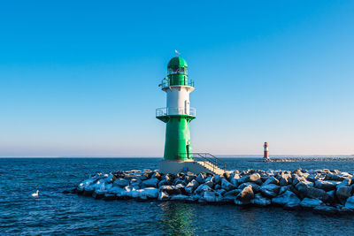 Lighthouse by sea against sky