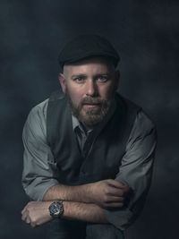 Portrait of mature man sitting against gray background