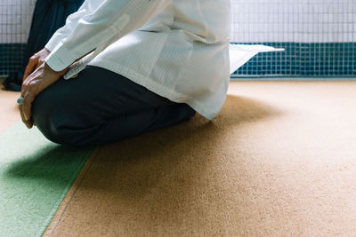 Low section of woman sitting on carpet at home