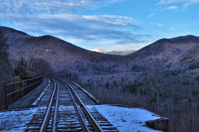 Railroad tracks amidst mountains against sky