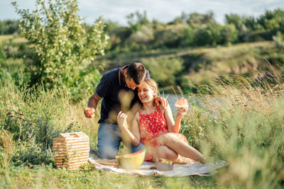 Young couple in love on summer picnic with watermelon. loving couple sitting by the river, talking