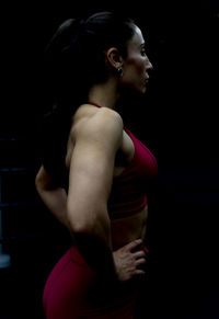 Side view of woman with hands on hip against black background