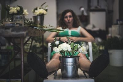 Close-up of potted plant with woman sitting on chair in background