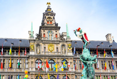 Low angle view of brabo fountain against antwerp city hall at grote markt