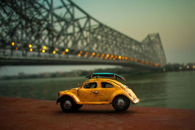 Yellow toy car on bridge against sky